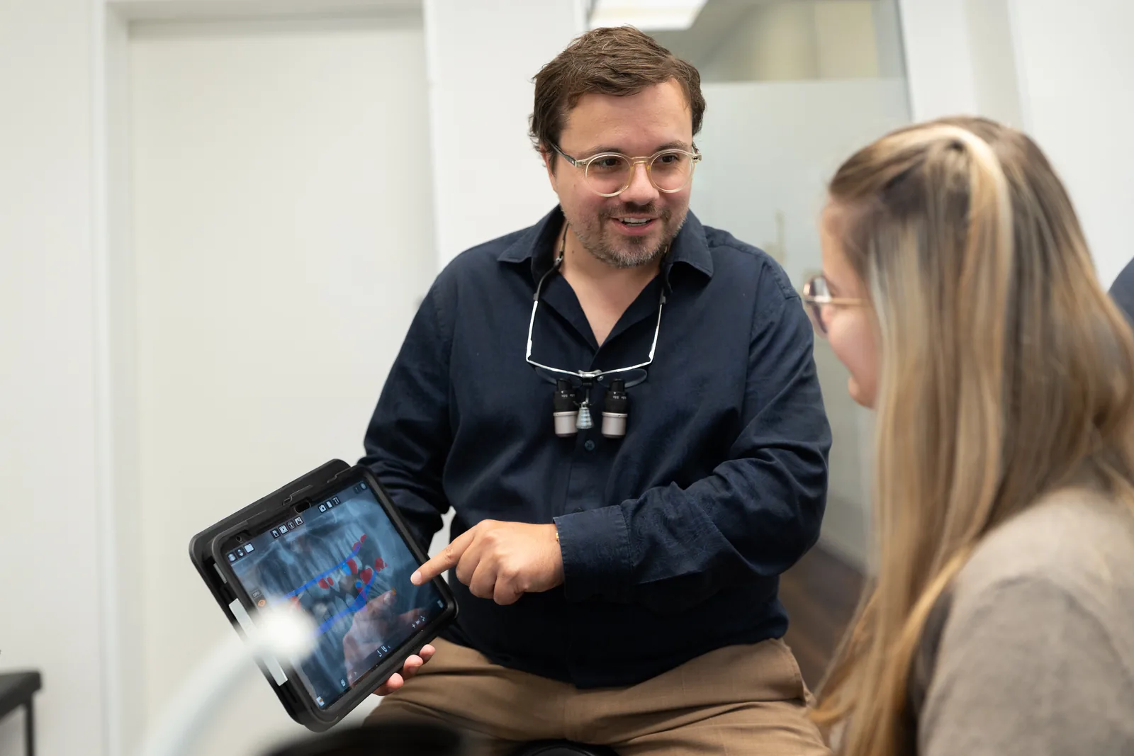 Dr. Strößner explains the implant plan to a patient on the X-ray image on the tablet